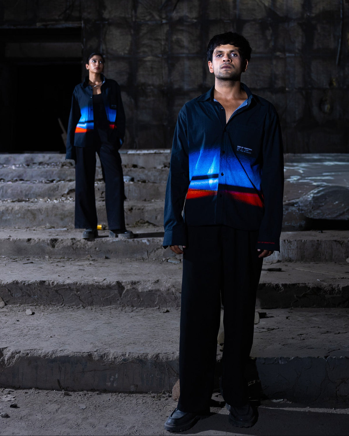 Two people wearing reflective vests standing on steps in a dark setting