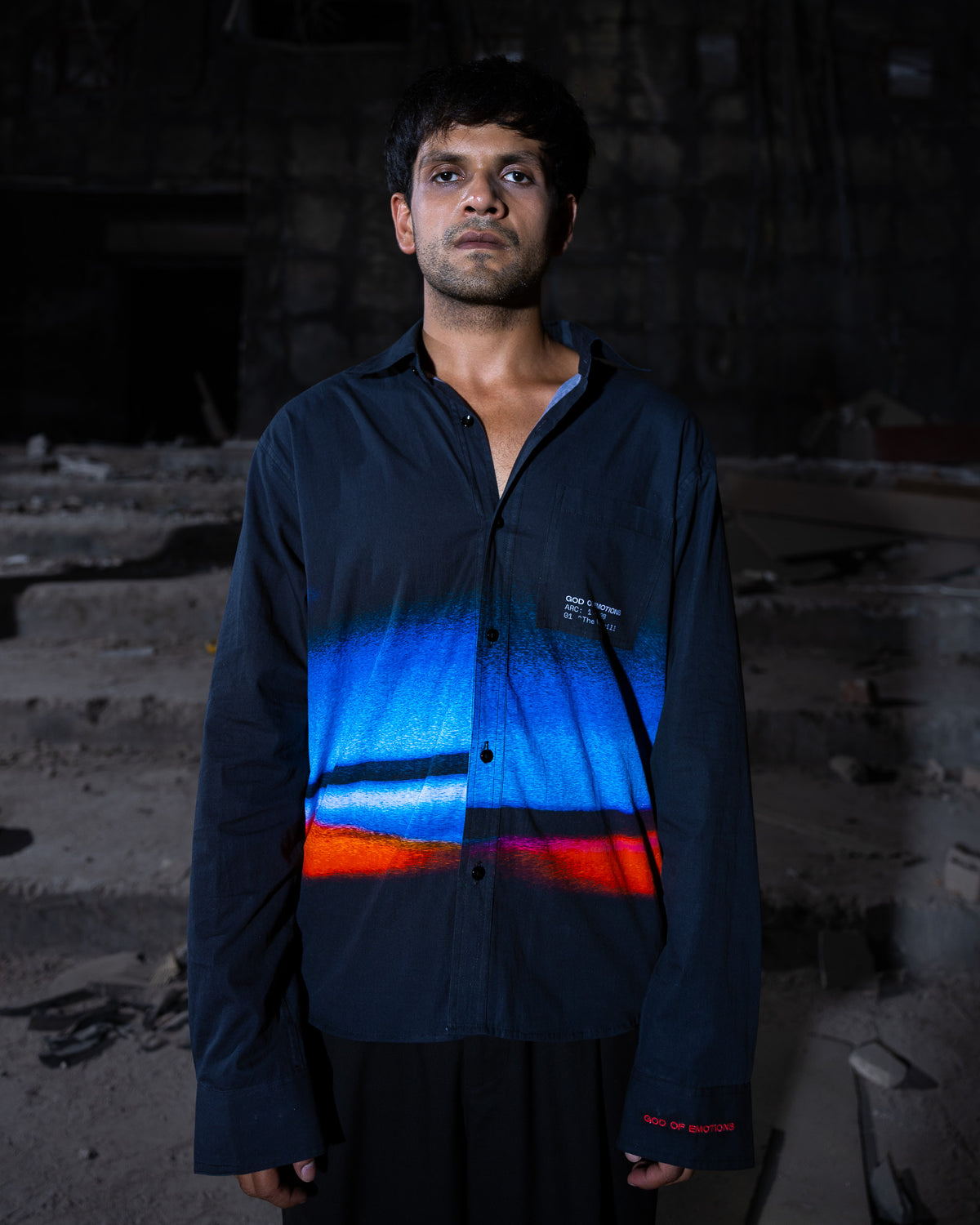 Man wearing a reflective safety jacket with blue and orange stripes in a dark setting